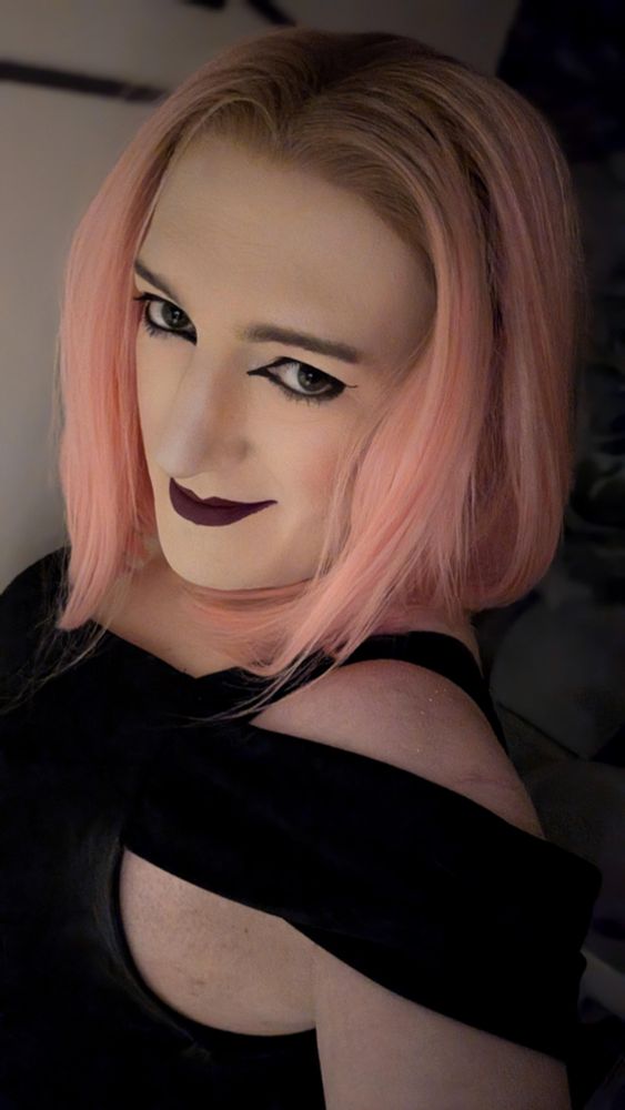 Selfie of my beautiful girlfriend Maddie, pink haired, wearing a black dress and a wan smile.