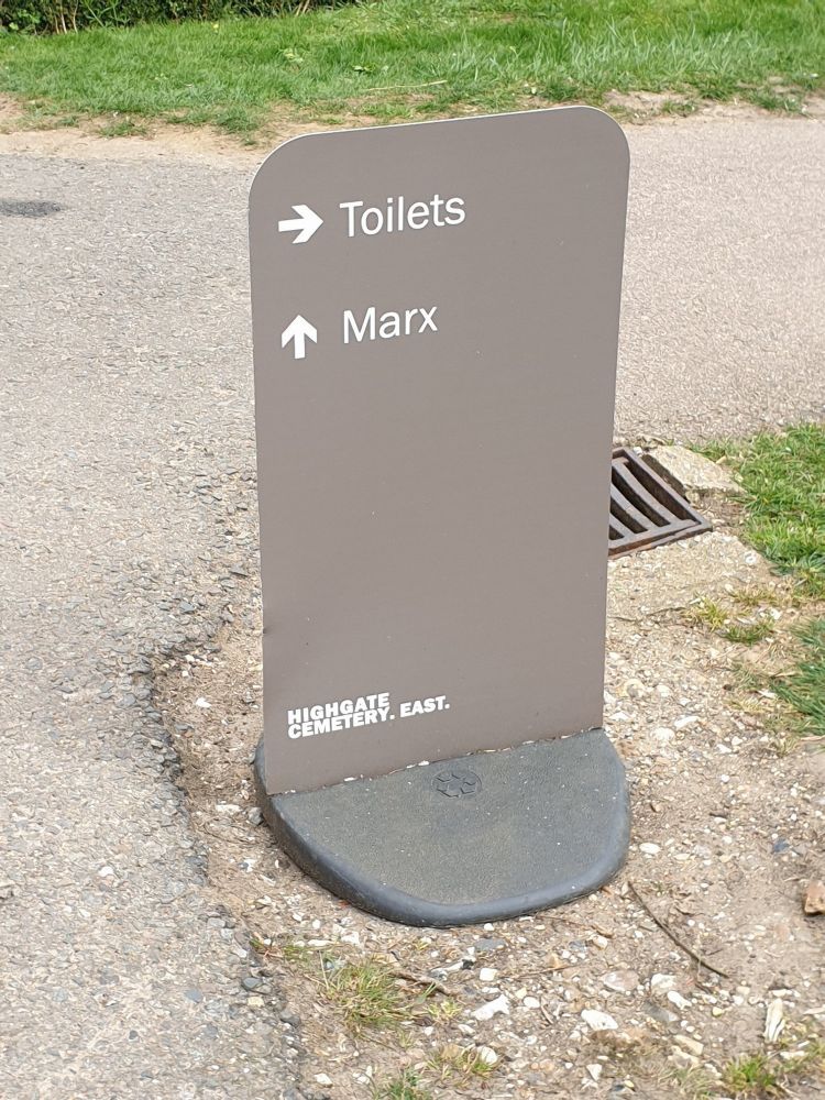 A sign at Highgate Cemetery with two arrows directing visitors to "toilets" and "Marx" respectively