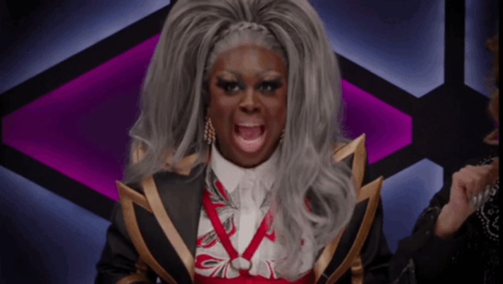 a drag queen with gray hair is wearing a black jacket