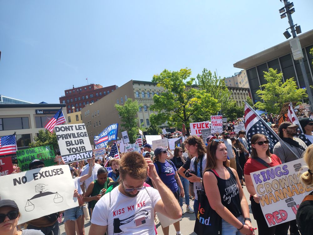 Protestors with signs and American flags at Rosa Parks Circle. 