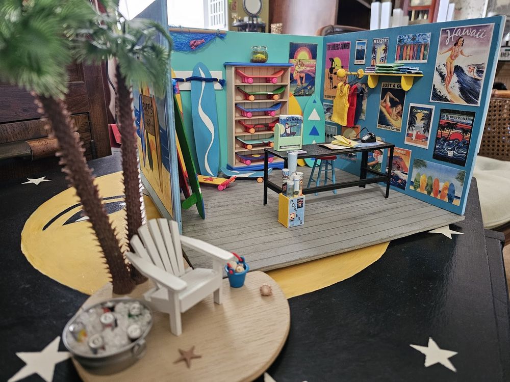 photo of miniature surf shop, complete with tiny beach posters on the wall, hanging clothes and itty bitty surfboards