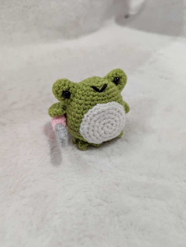 Une grenouille verte qui tient son couteau au beurre faut au crochet.