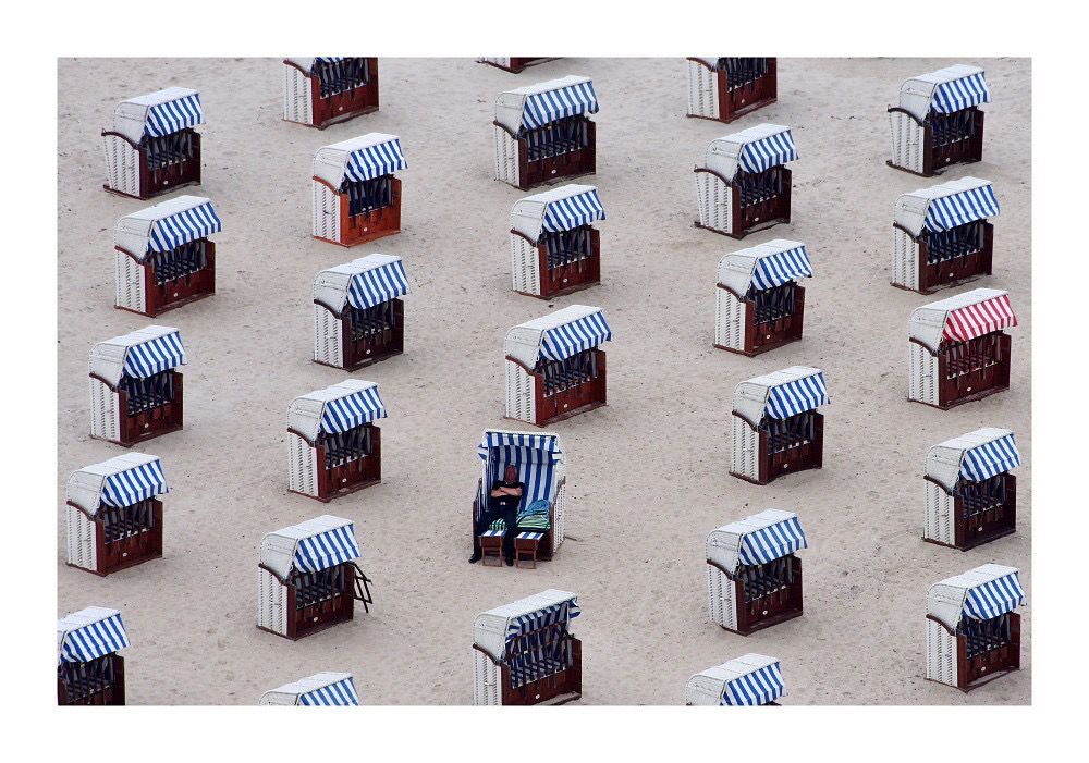 Strandkörbe in Travemünde von schräg oben aus dem Maritim Hochhaus. Alle Strandkörbe stehen in Reihe und Glied - einer wurde jedoch von einem Sonnenfreund gedreht