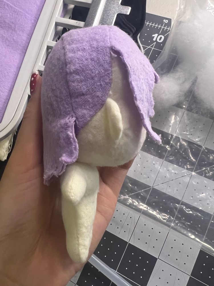 handmade plush doll of noelle as seen from the side. The body is offset back from the head in a way that looks unnatural. There is a large gap between the bangs and head, and the edges of the hair cloth are frayed.