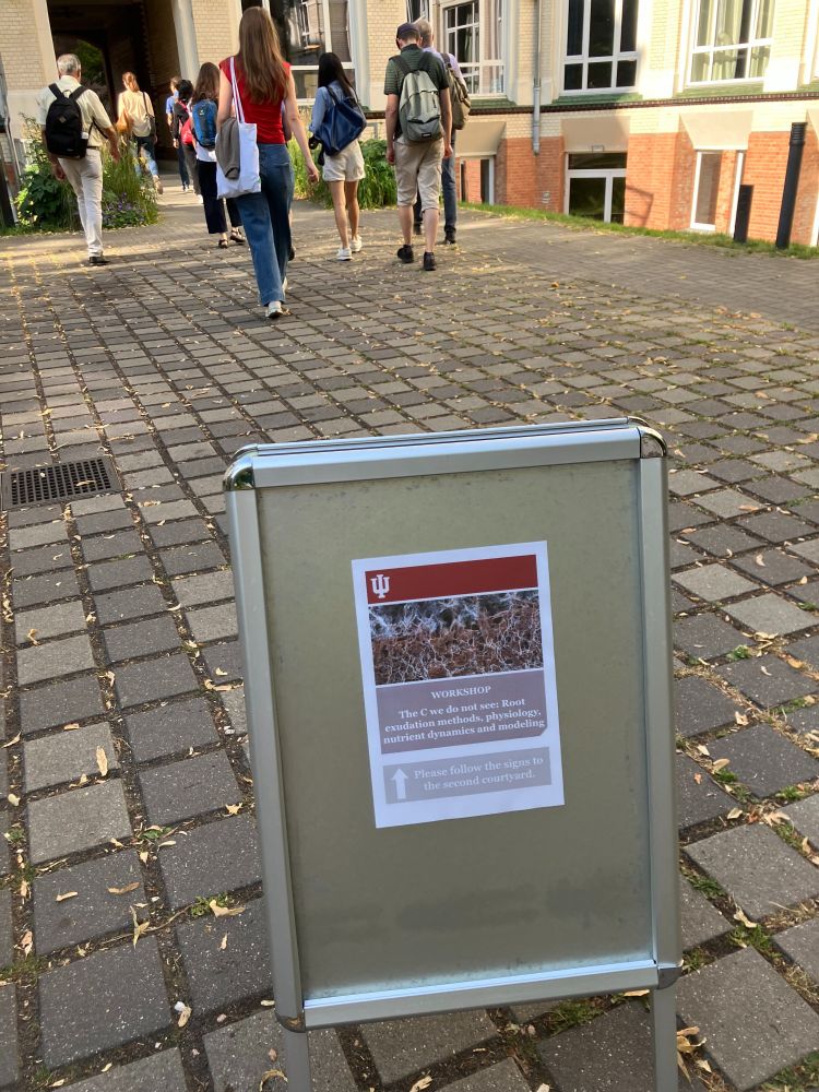 The courtyard of the workshop venue, with a sign pointing us to the right room for the workshop "The C we do not see: Root exudation methods, physiology, nutrient dynamics, and modelling"