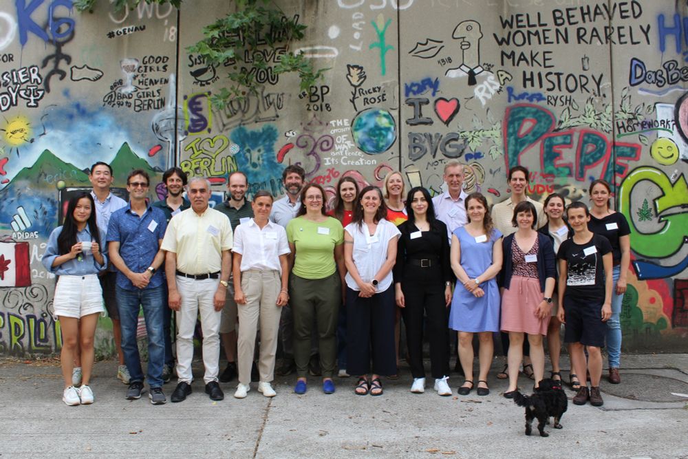 A group photo of all participants in front of a large graffiti mural
