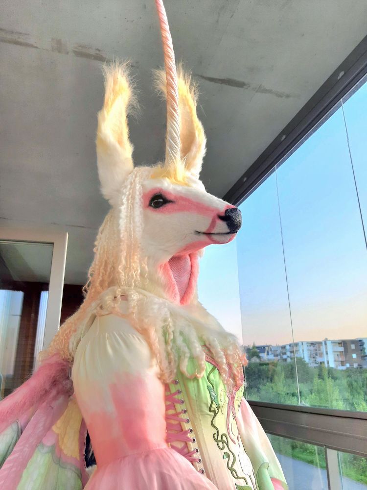 Photo (upper-body view, facing right) of my new Lunacorn fursuit, doing wing tests on our apartment balcony at sunset. 