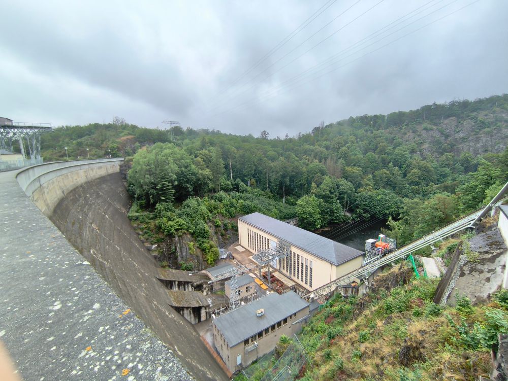 Das Turbinenhaus unterhalb der Staumauer mit der zwischen Hügeln entlangfließenden Saale 