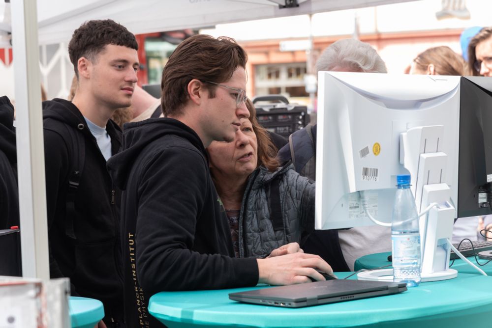A scientist explains an experiment which can be seen on a monitor to a visitor.