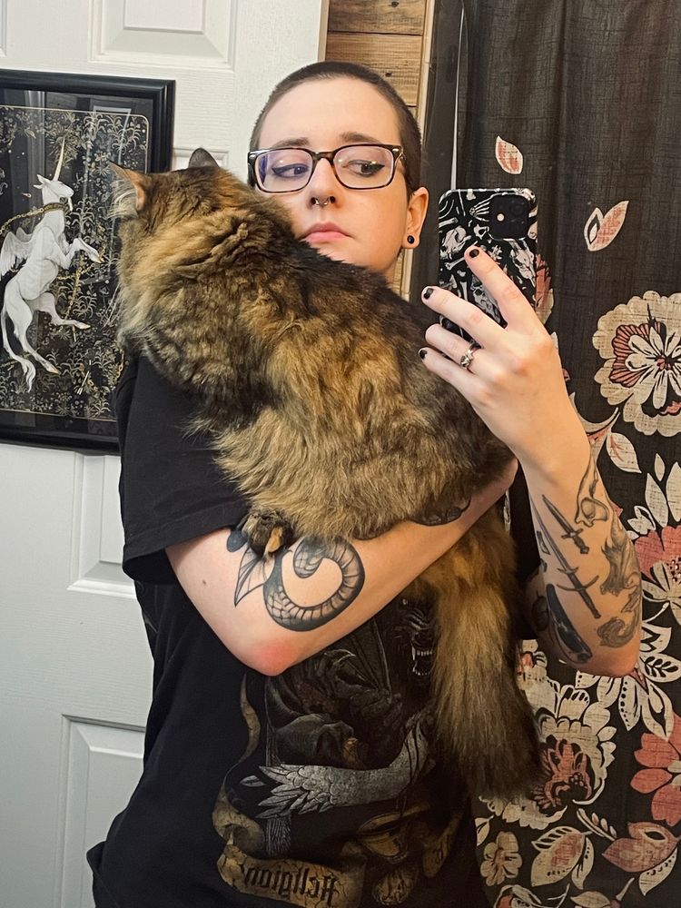 Bathroom mirror selfie of a person in black with a very fluffy cat in their arms