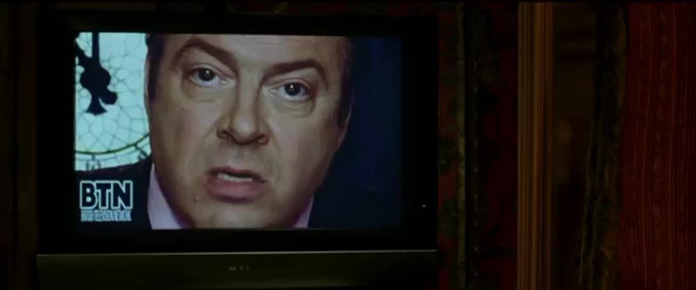 A scene from V for Vendetta where Lewis Prothero is on television spreading government propaganda.