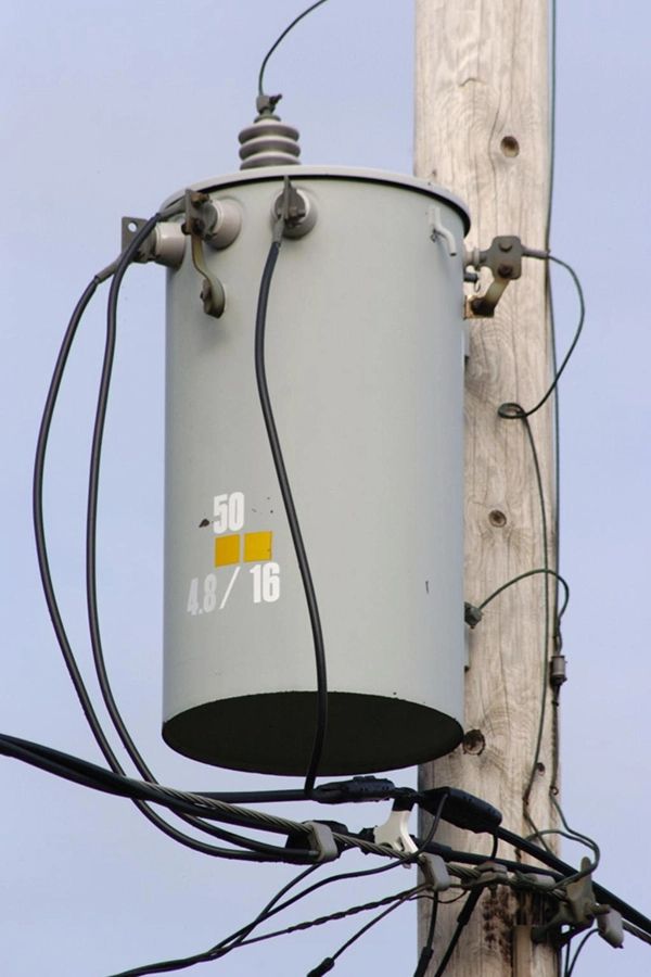 An electricity transformer mounted on a telephone pole.