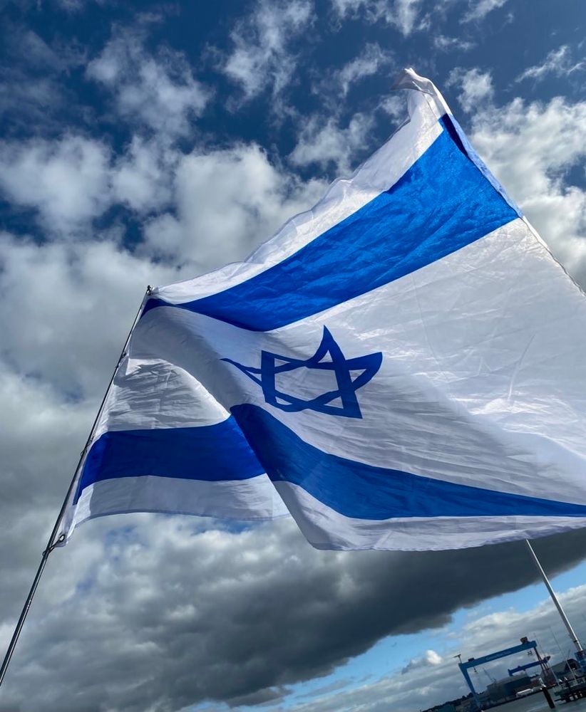 Flagge von Israel weht im Wind vor wolkigem Himmel. 