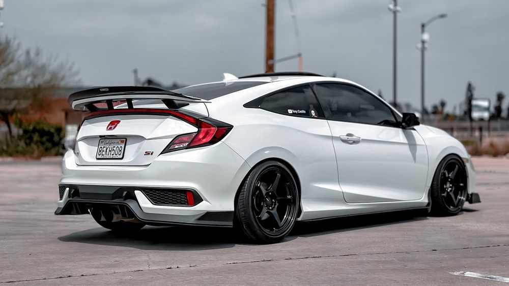 a white car; a tenth generation honda civic si coupe. it looks more distinctly geometric and sporty, with a more prominent spoiler and sharp, angular taillights.