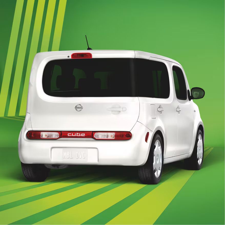 a photo of the real Nissan Cube. a feature that distinguishes it from other cube-shaped cars is the rear windshield, which wraps around just one side of the vehicle to almost seamlessly connect with the backseat window