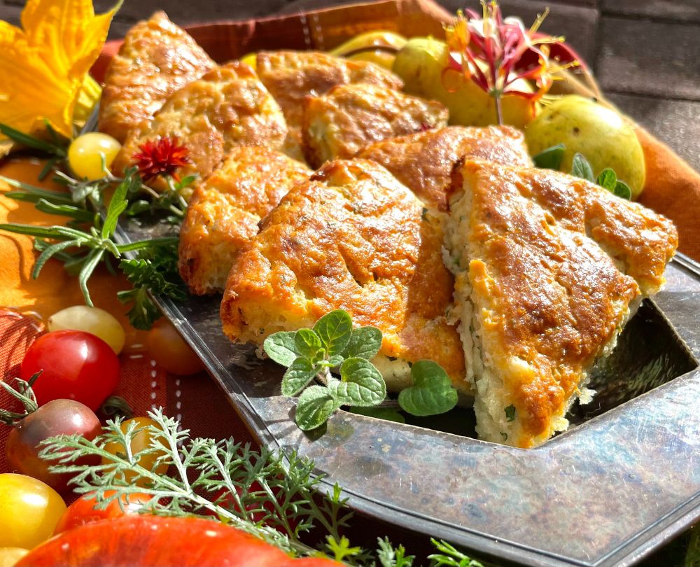 Metal oval plate holds eight triangular potato and herb scones.