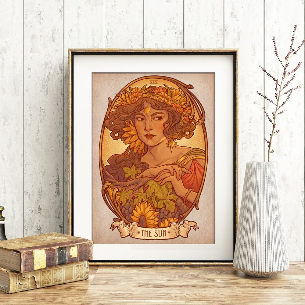Una lámina enmarcada con una señora que representa el sol en el tarot. Está flanqueada por decoración como libros antiguos y un jarrón