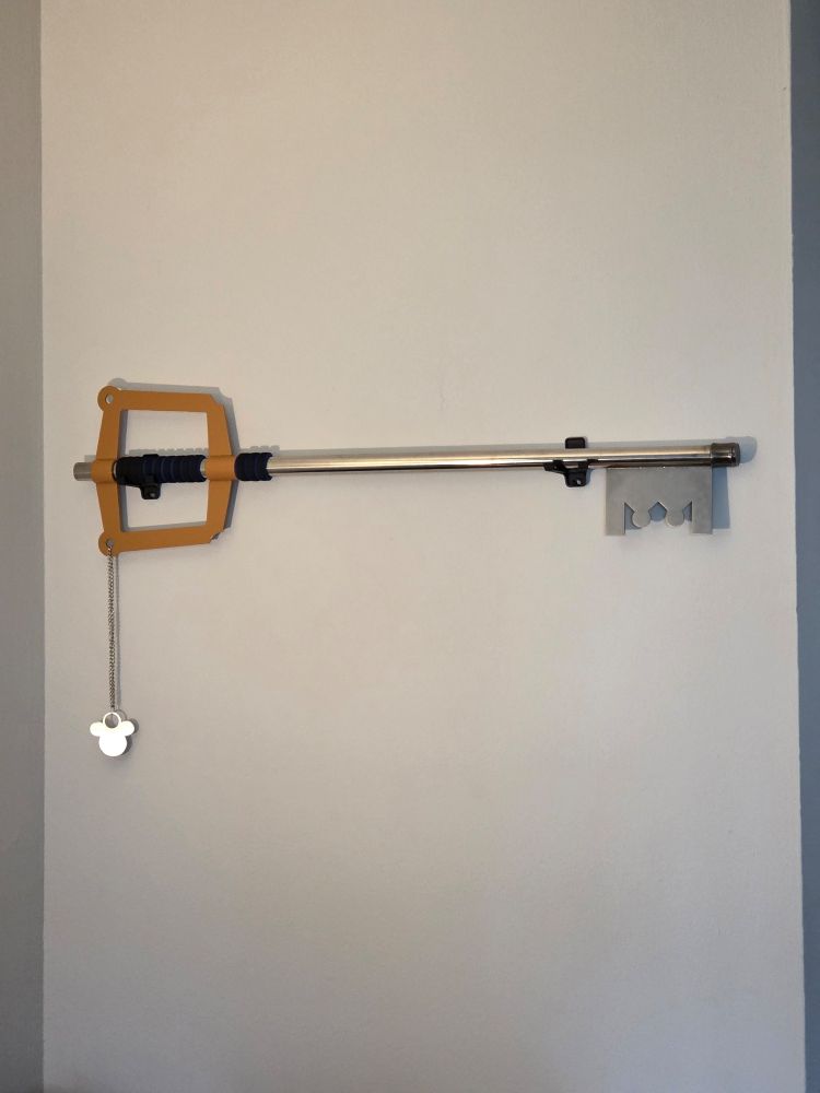 A replica of a Keyblade from Kingdom Hearts mounted on a white wall 
