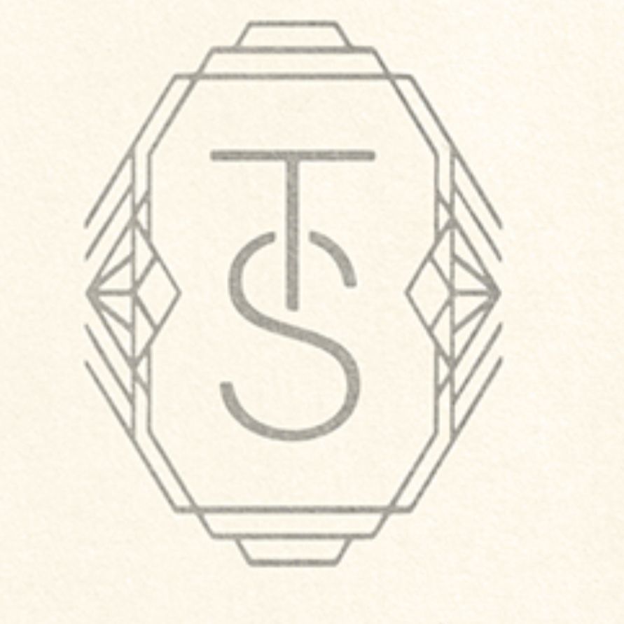 A grey logo on an off white background which was printed at the top of Taylor Swifts “my letter” following her record reclaim. It shows a diamond shape with the letters TS in the middle, merging into one another. At the sides are two sideways miniature diamond drawings. (Or jewels) 
