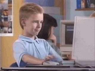 Boy in front of computer who does a thumbs up gesture. 