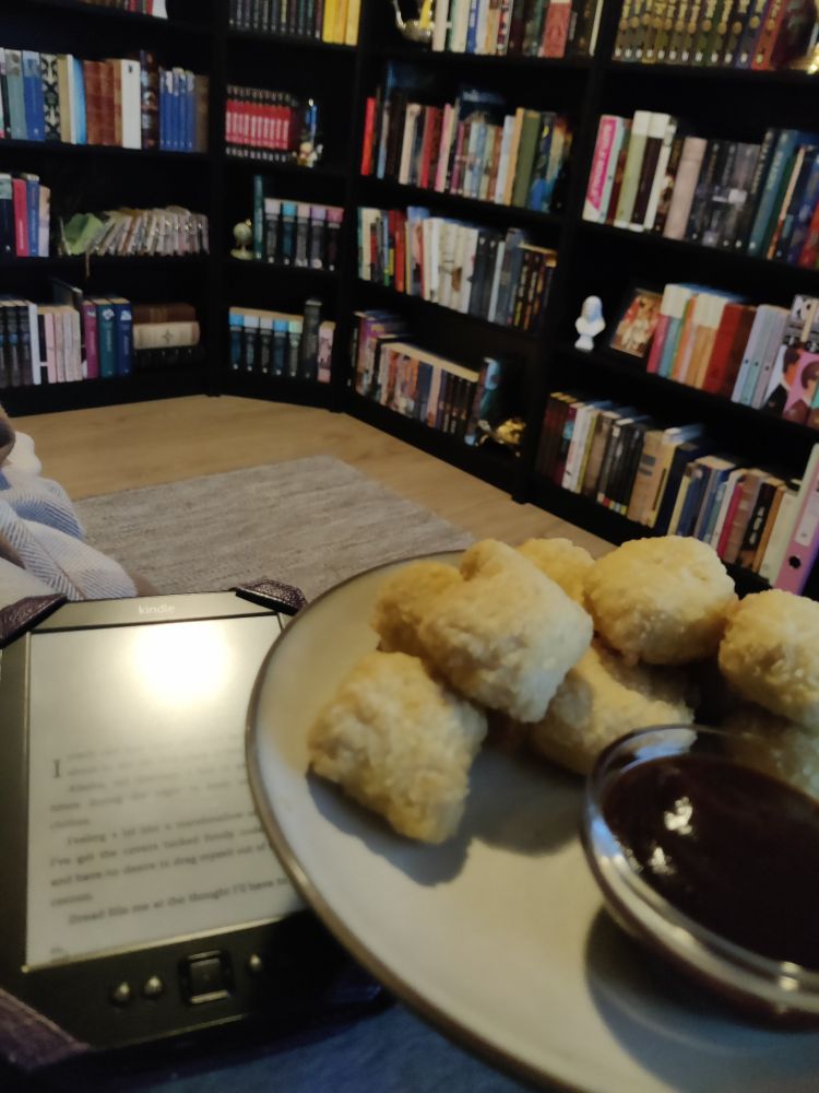Bilde av en Kindle og en asjett med kyllingnuggets foran en bokhylle.