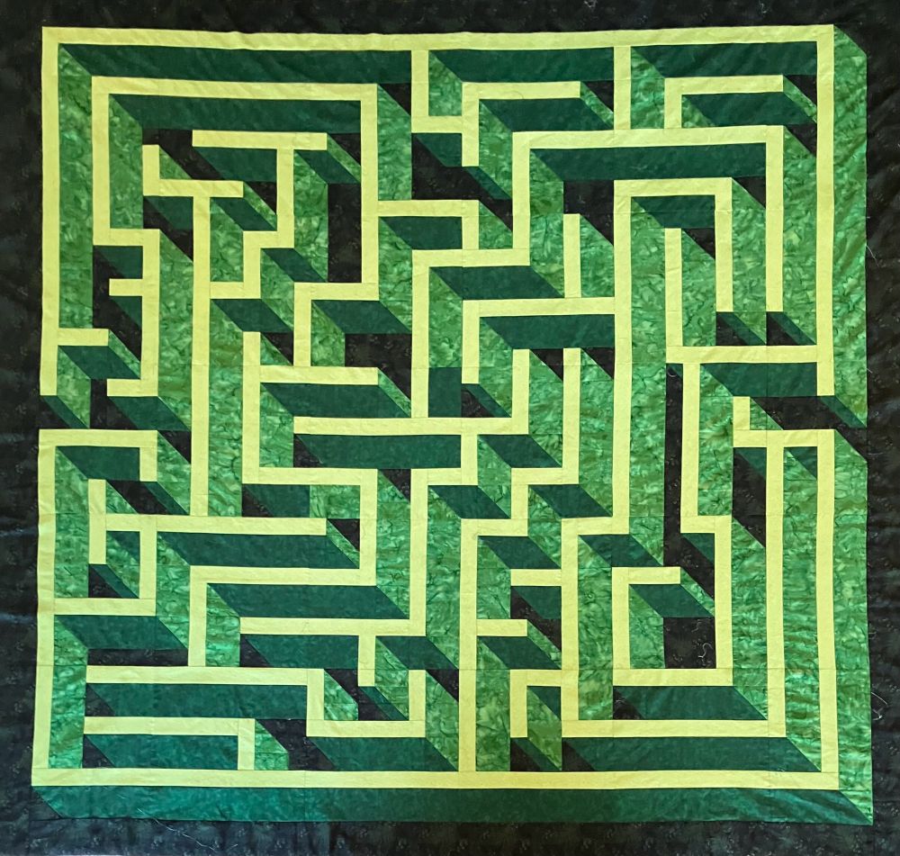 Quilt made in tones of green, looks like a hedge maze