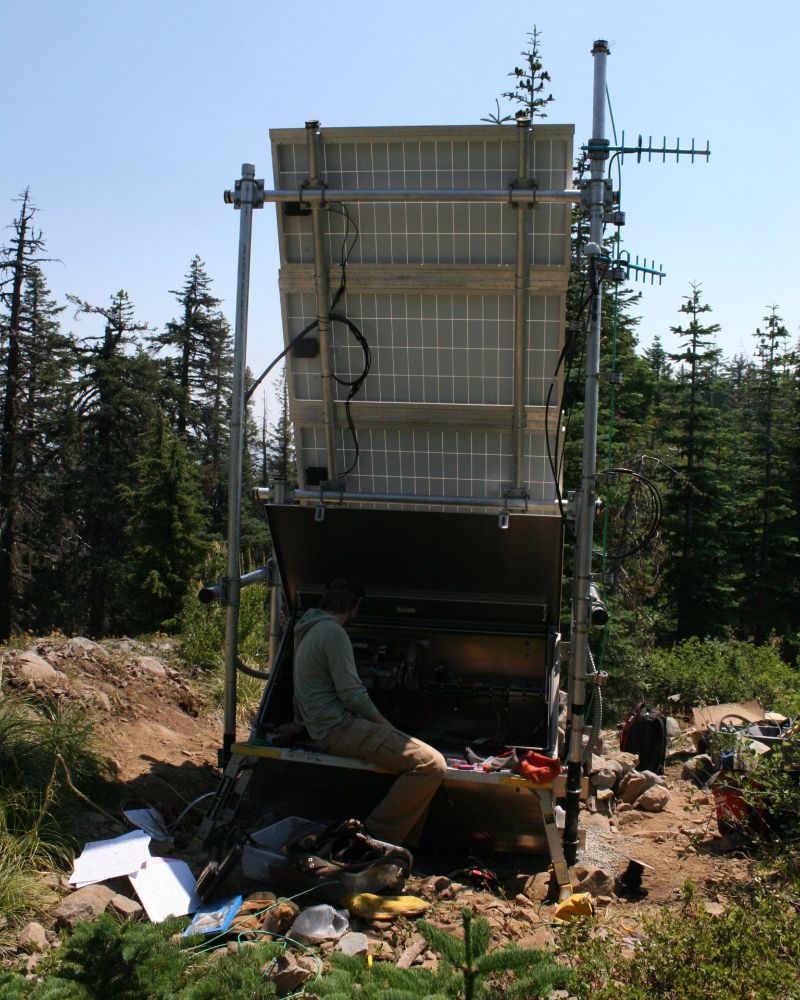 A young man works on equipment at a seismic monitoring station.