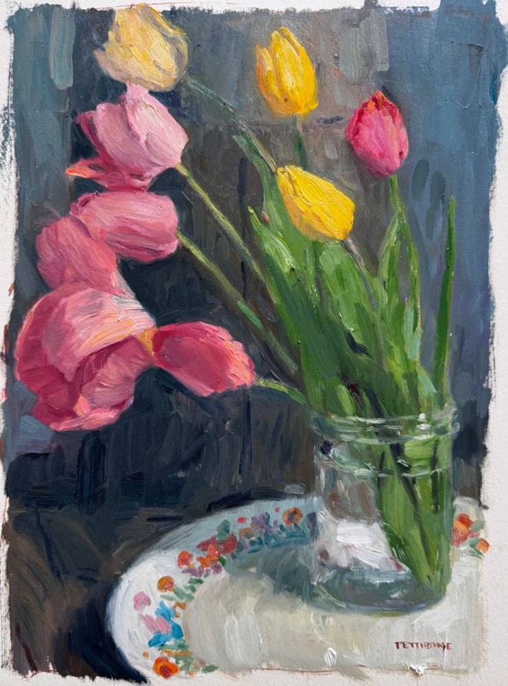 An oil painting of bright tulips in a jar against a dark background on a colorful plate. 