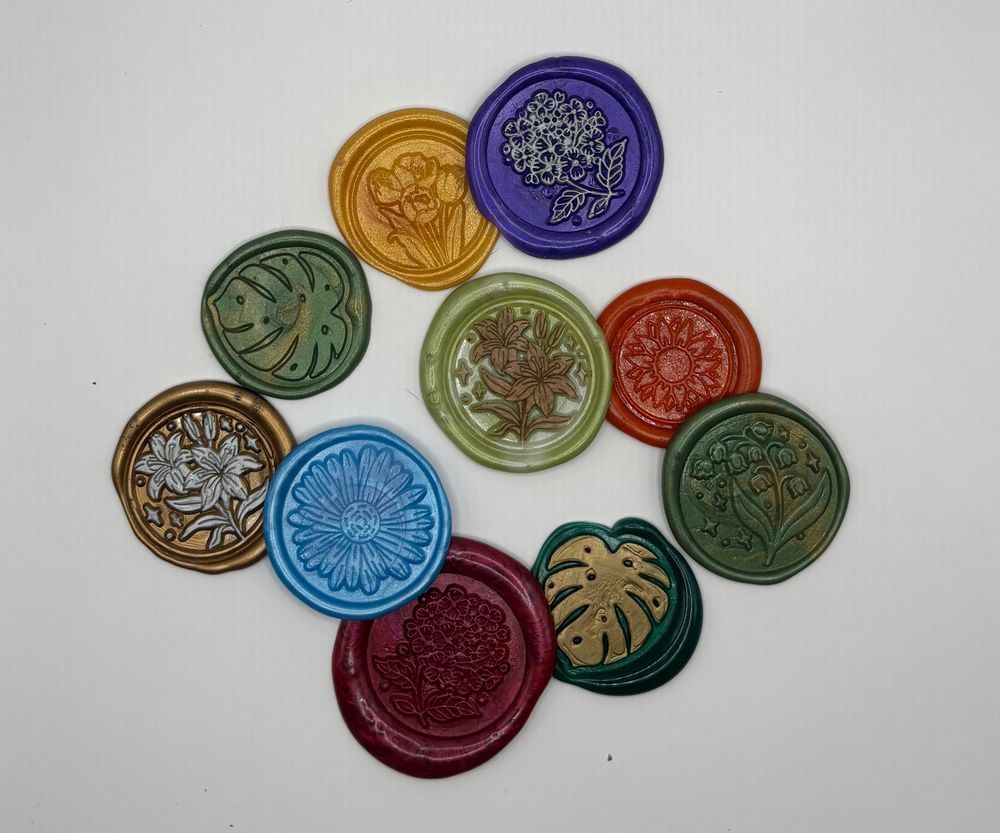 A set of 10 wax seals in an assortment of colors. Each has a floral print - there are tulips, lilies, hydrangeas, sunflowers, daisies, lily of the valleys, and monsters leaves.