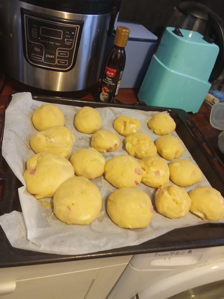 Sur une plaque de cuisson 17 petits pains en boule avec de la mozarella et du jambon 