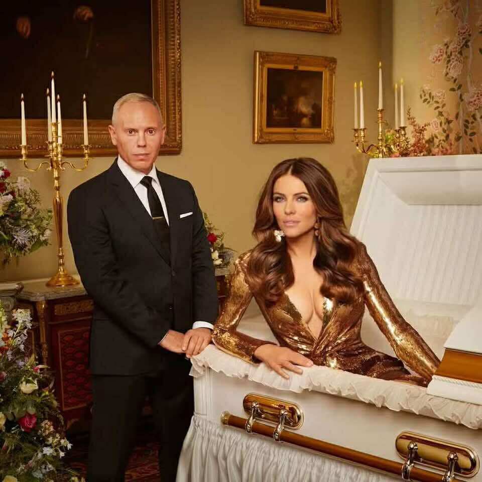 Rob Rinder stands next to Liz Hurley who has risen from the dead out of her coffin 