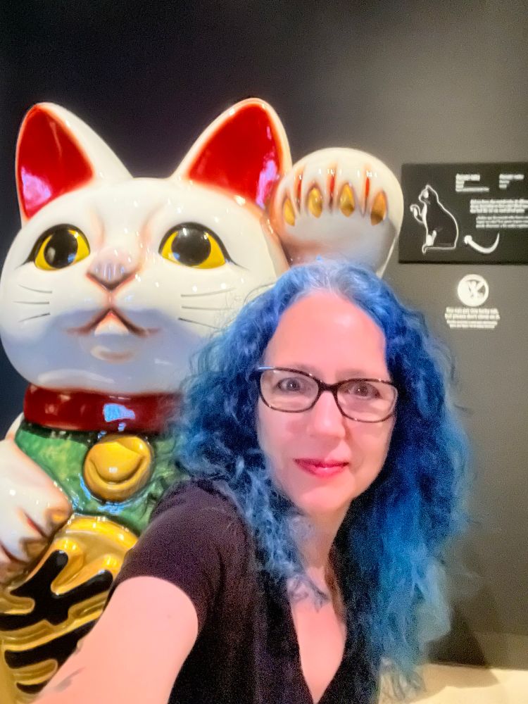 Me, a woman with blue hair, with a giant “good luck cat”