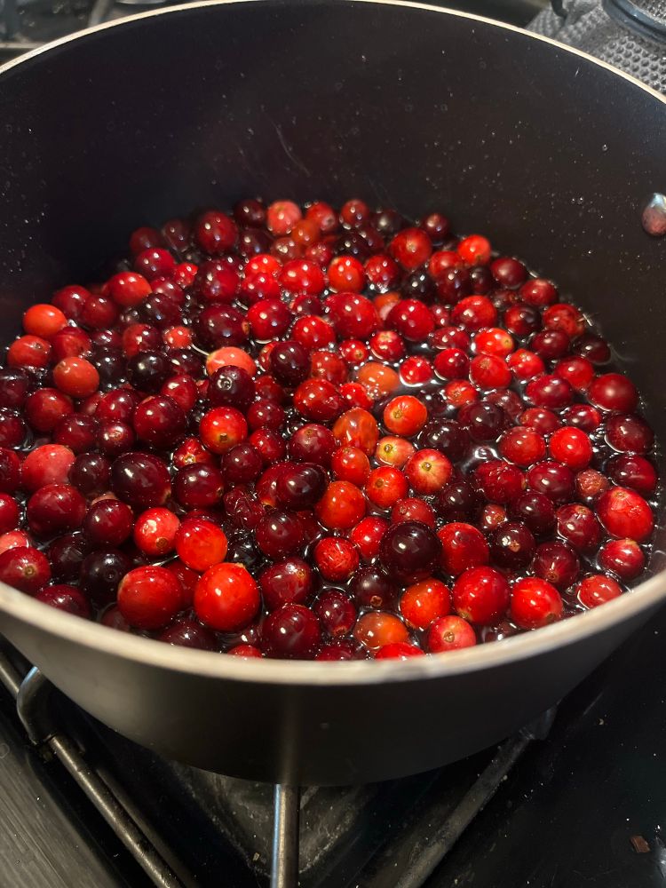 Cranberries in a pot becoming cranberry sauce 