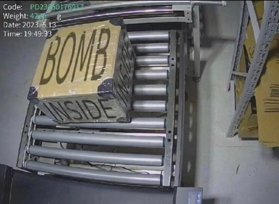 Picture of a large box at a shipping facility marked “BOMB INSIDE” 