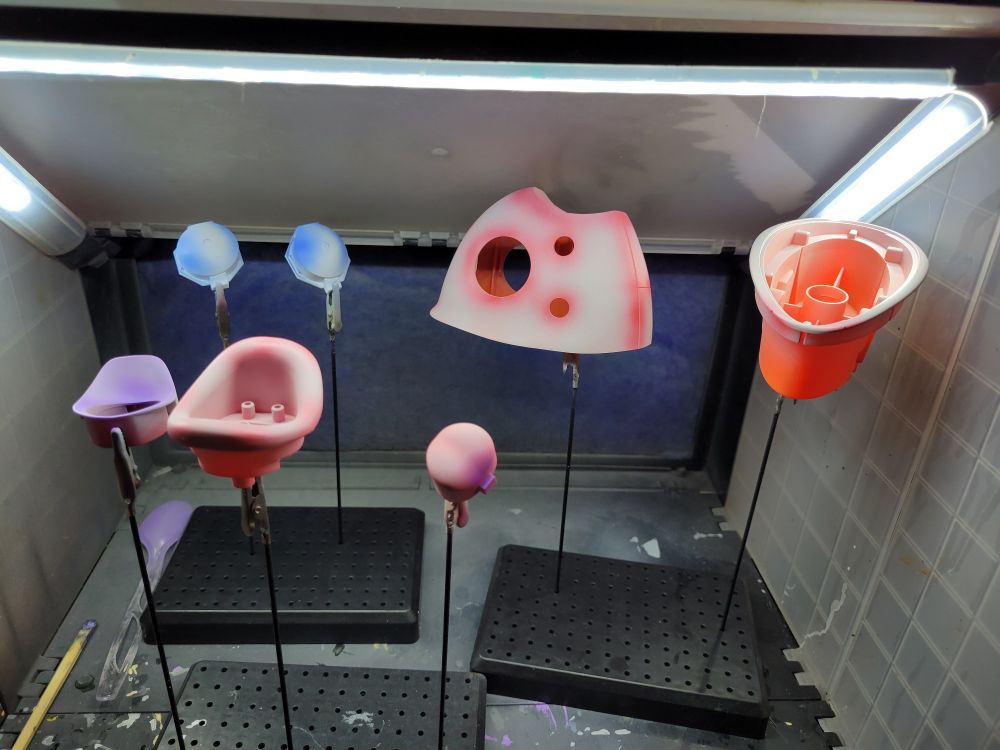 Model parts for what is obviously a magikarp from pokemon. The bits that won't be exposed are still raw plastic, but a grey primer covers the exposed parts. Each part has a second color that is an high saturation at places where you'd get shadows. (This practice is known as pre shading)