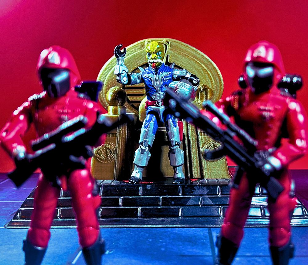 Photo of GI Joe action figures. Cobra Commander, wearing his battle armor, is in the background standing in front of his throne. He is shaking his feet. His helmet is clasped under his left arm, leaving him unmasked. He has a weird alien snake face. He is flanked by two Crimson Guards in the foreground. 