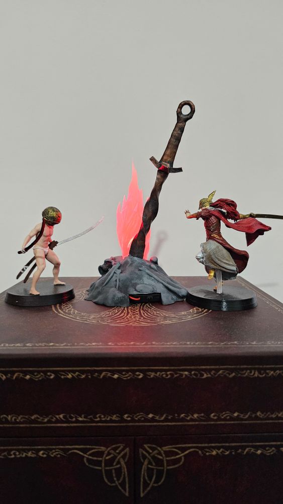 Foto com três miniaturas de Elden Ring: uma da fogueira, uma da Malenia e uma do personagem que ficou conhecido como Let Me Solo Her