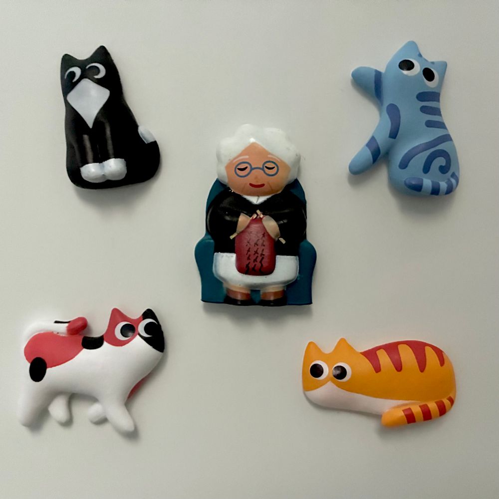 Juego de imanes de nevera “Cat lady magnets” compuesto por una dulce ancianita que teje en su sofá y cuatro gatetes, cada uno de su padre y de su madre
