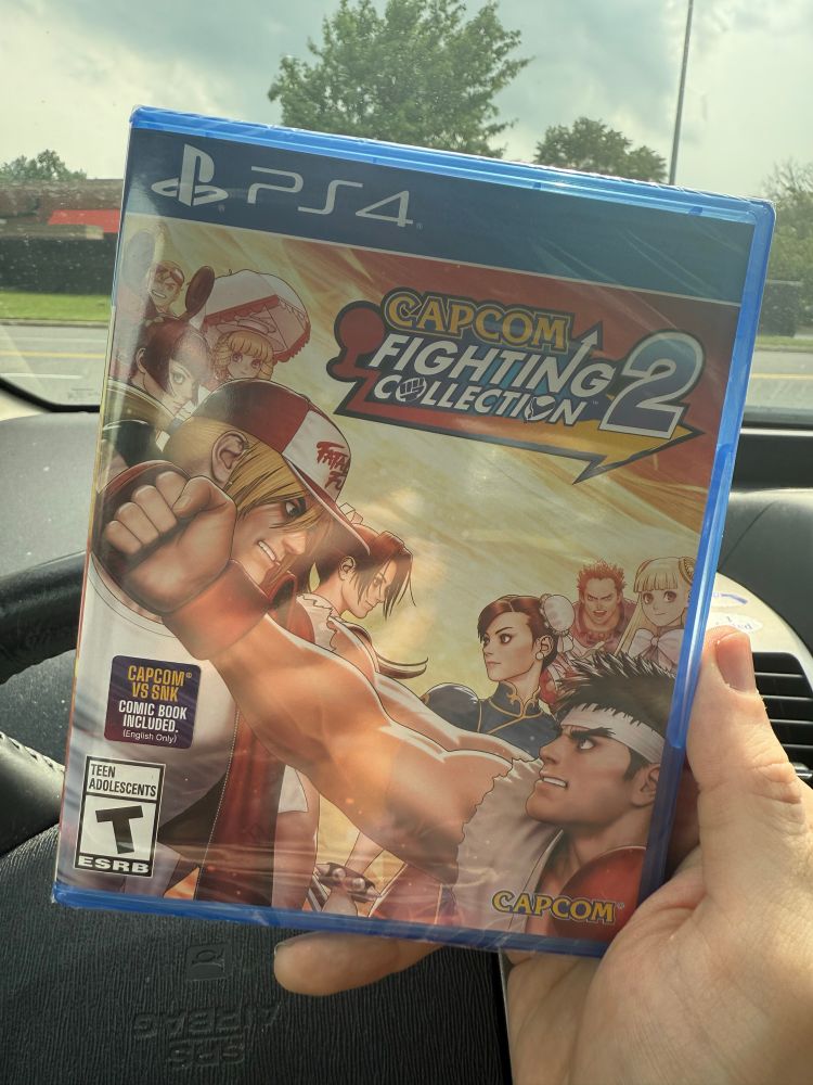 A copy of Capcom Fighting Collection 2 for the Playstarion 4. It’s held inside a car, which itself sits in the parking lot of a shopping mall. There was once an arcade at this very same mall that had CVS2. This disk looks to be jam packed with Dreamcast era must plays.