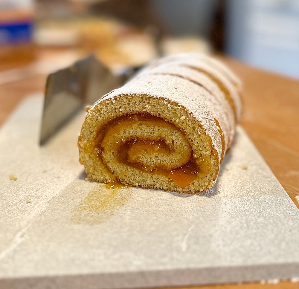 A fancy shot of a cross section cut of the cake roll (jelly roll) with peach preserves.