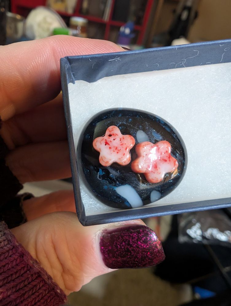 A dark blue circle of blue glass mixed with white with 2 pink and white star eyes 