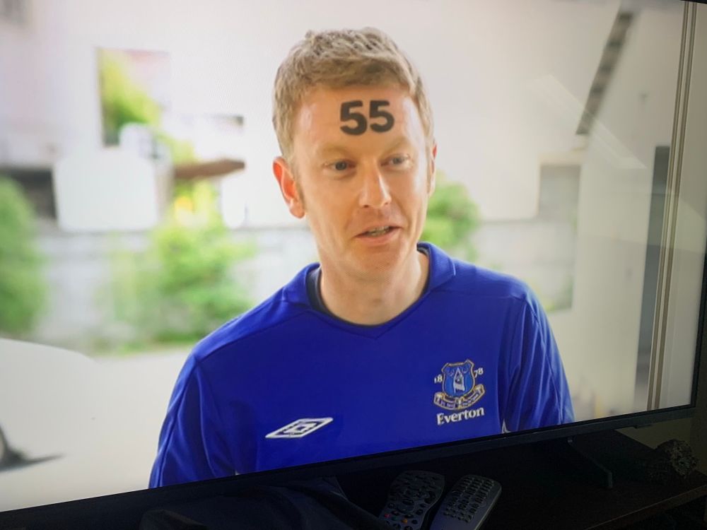 A white man in an Everton training top with the number 55 stamped on his forehead.