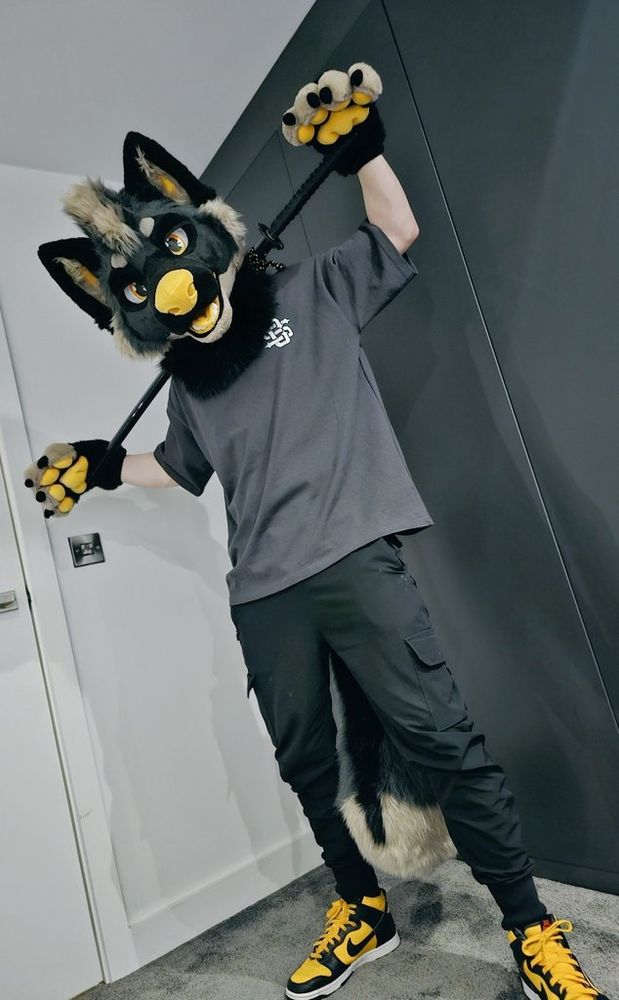 Kage fursuit holding a katana between his shoulders.
