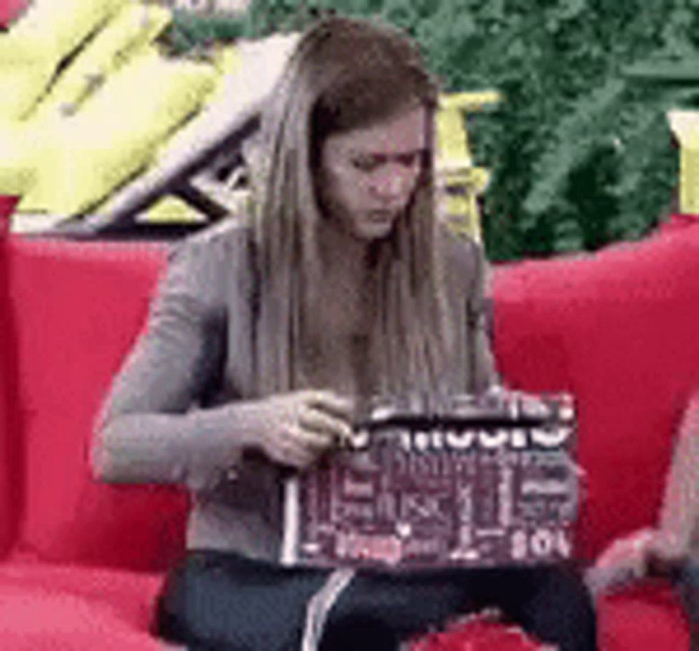 a woman is sitting on a red couch looking at a laptop .