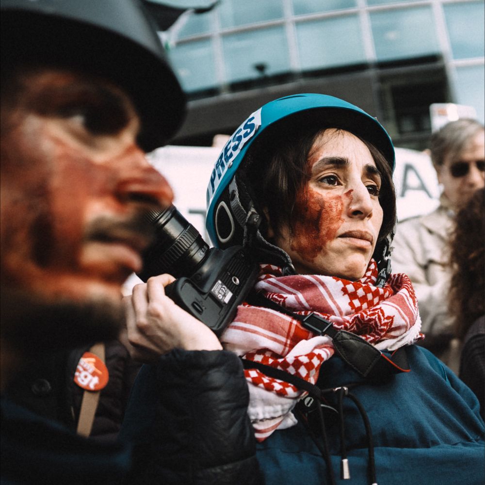 Deux journalistes casqués, avec des traces de faux sang sur le visage.