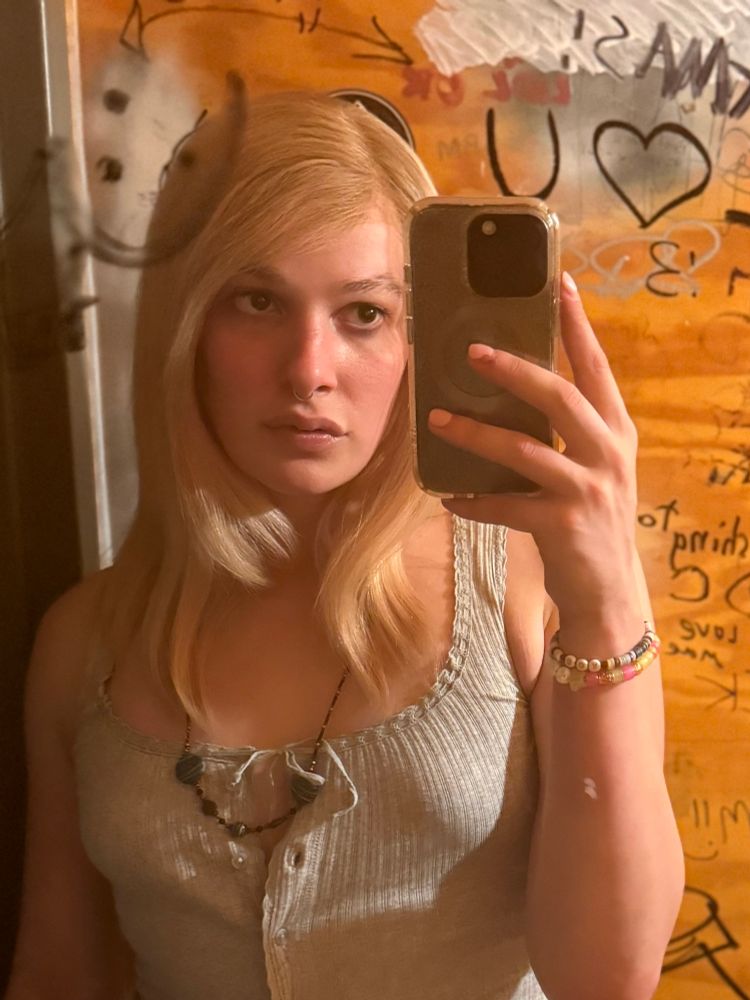 Jael poses in a mirror of a bathroom 