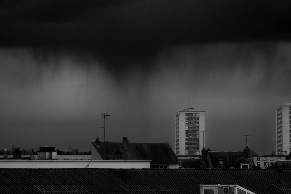 Une photo d’horizon de Tours, avec deux immeubles qui ressortent, et un ciel de pluie très sombre au loin qui laisse tomber des "fils" d’eau visibles