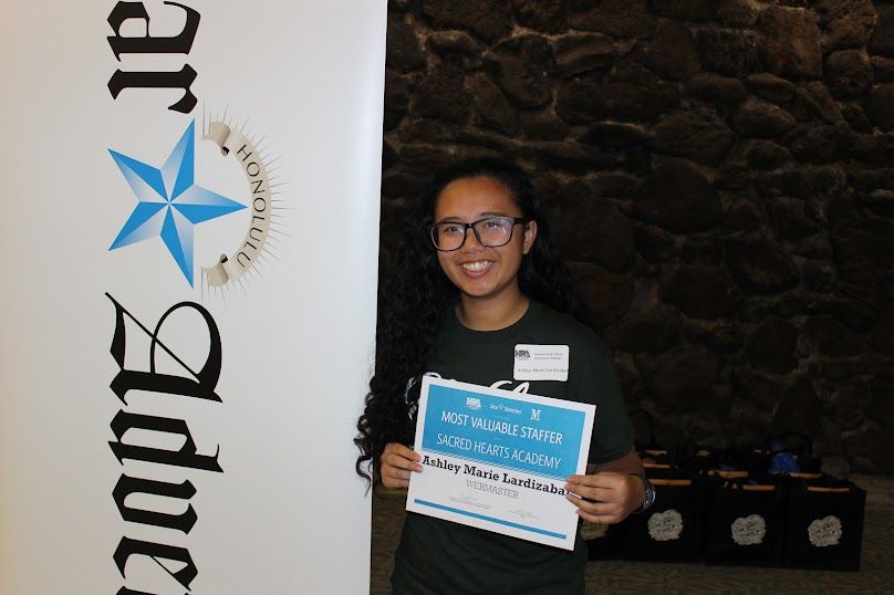 Smiling photo of Ashley Marie — in a black shirt with black glasses — holding a blue and white  award certificate. Text says: “Most Valuable Staffer; Sacred Hearts Academy; Ashley Marie Lardizabal, Webmaster” 