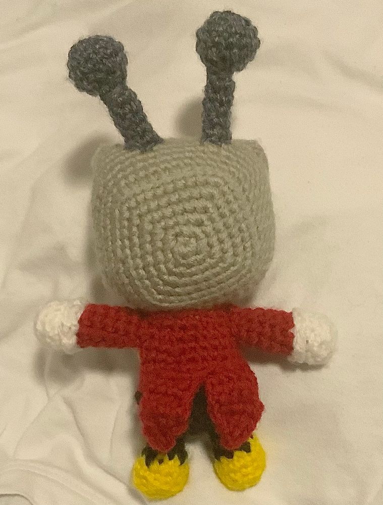 A back view of the mini crochet doll of Tenna (from Deltarune) that I made!
From this angle you can see the back of the TV head, and better see the coattails sewn onto the back of his suit!