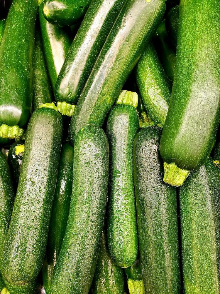 close up of a lot of zucchinis, some with a dewy spray
